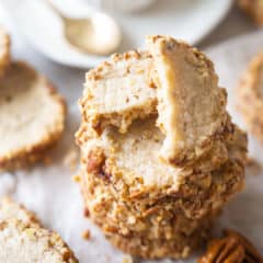 Close up image of a stack of pecan sandies rimmed in chopped pecans.