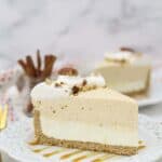 A big slice of pumpkin mousse cake on a white plate that drizzled with caramel sauce