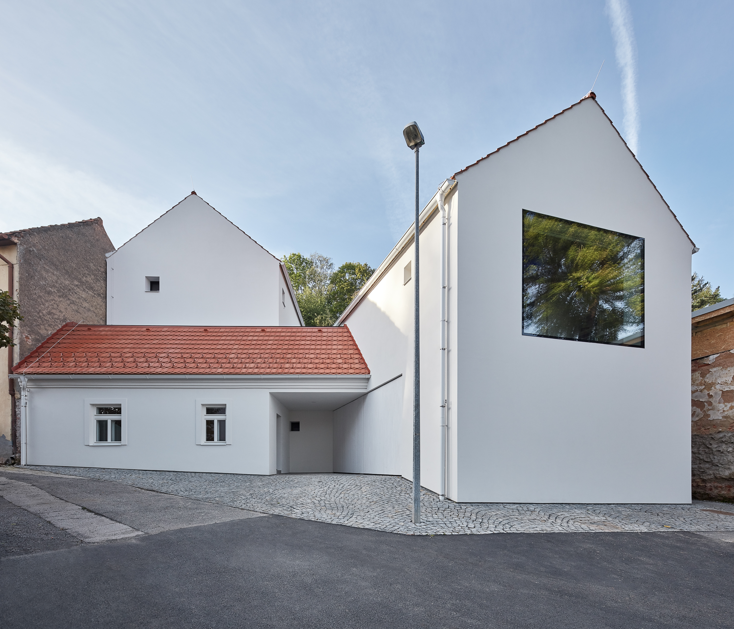 White house with red tiled roof and a large square window.