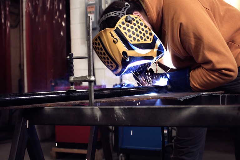 welding student wearing a helmet welding a project