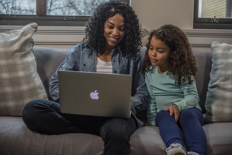 mom on couch on laptop with daughter