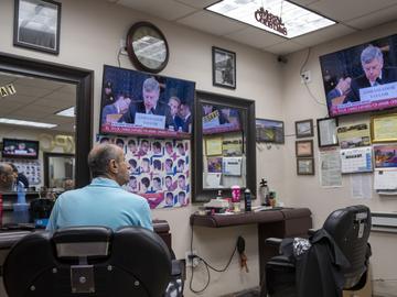 Barber Nat Yunayed watches impeachment hearings while waiting for customers in New York City on Wednesday, Nov. 13, 2019.