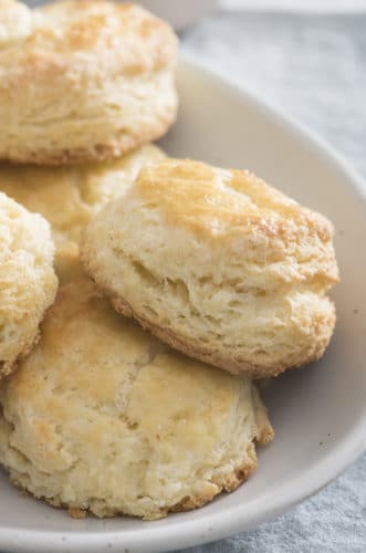 A photo of a soft pink plate holding fluffy buttermilk biscuits.