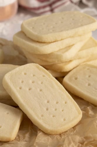 A group of shortbread cookies. some are stacked while others are on crumpled paper.