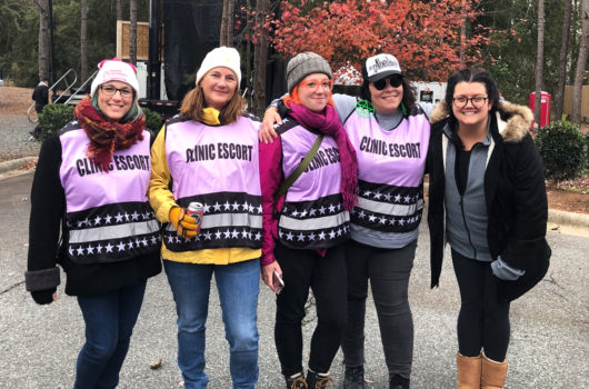 [Photo: A group of clinic escorts pose outside for a photo.]