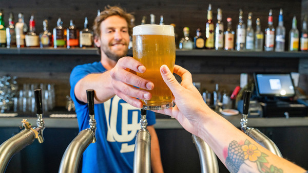 Barkeeper reicht ein Bier