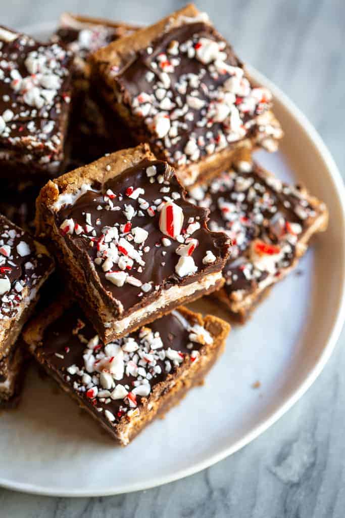 Peppermint Brownie squares with chocolate frosting and crushed candy canes, served on a white plate.