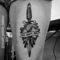 Black heart and dagger tattoo on thigh