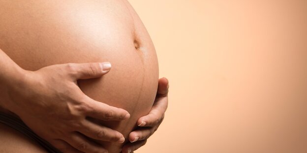 Eine Schwangere h&auml;lt die H&auml;nde an den Bauch