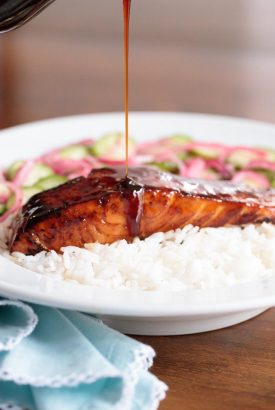 Vertical picture of honey coriander salmon with rice and sauce drizzled over the top in a white bowl