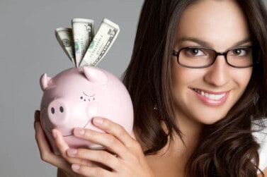 Smiling girl holding piggy bank money after saving using Trim