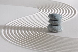Sand with Zen-style rake patterns and a stack of small stones.