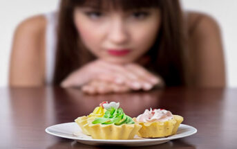 woman looking at cakes, trying to resist temptation by increasing her willpower