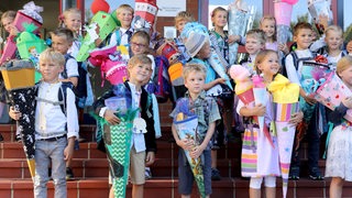 Erstkl&auml;ssler posieren bei ihrer Einschulung mit ihren Schlutüten.