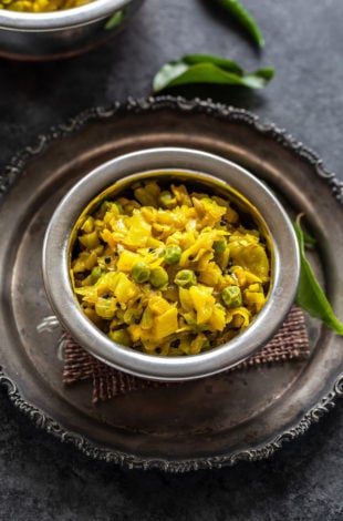 instant pot patta gobhi matar served in a small copper bowl and some curry leaves placed in the background
