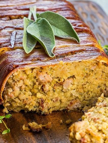 Bacon Wrapped Sausage Stuffing with a slice cut out of it showing the stuffing with sausage meat throughout