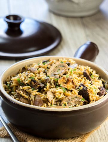 easy mushroom rice pilaf in a serving dish with the lid behind it