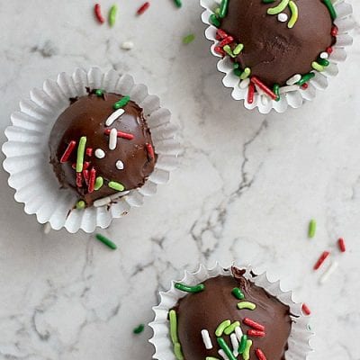 three chocolate truffles in small wrappers with holiday sprinkles