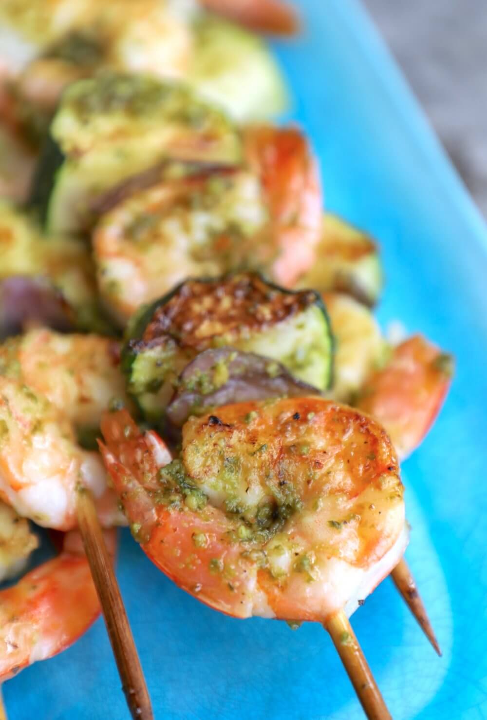 Keto pesto shrimp skewers on a blue platter