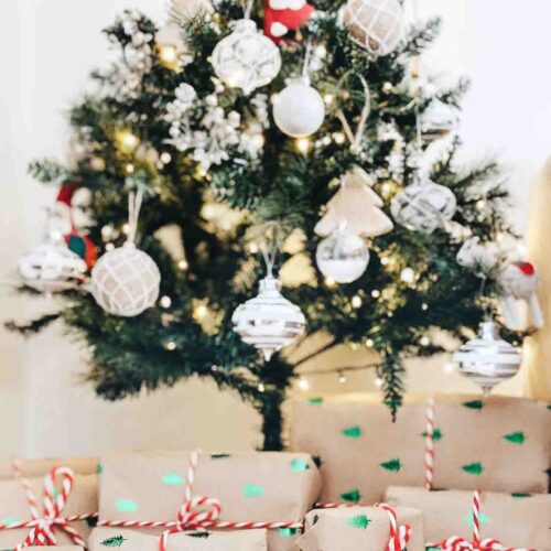 Wrapped gifts on the floor with decorated Christmas tree in the background.