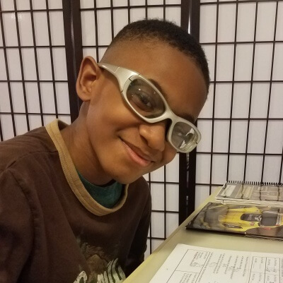 A smiling boy working on a Math Mammoth worksheet