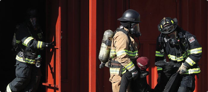 Three firefighters dressed in safety gear at a mock training for Medline employees