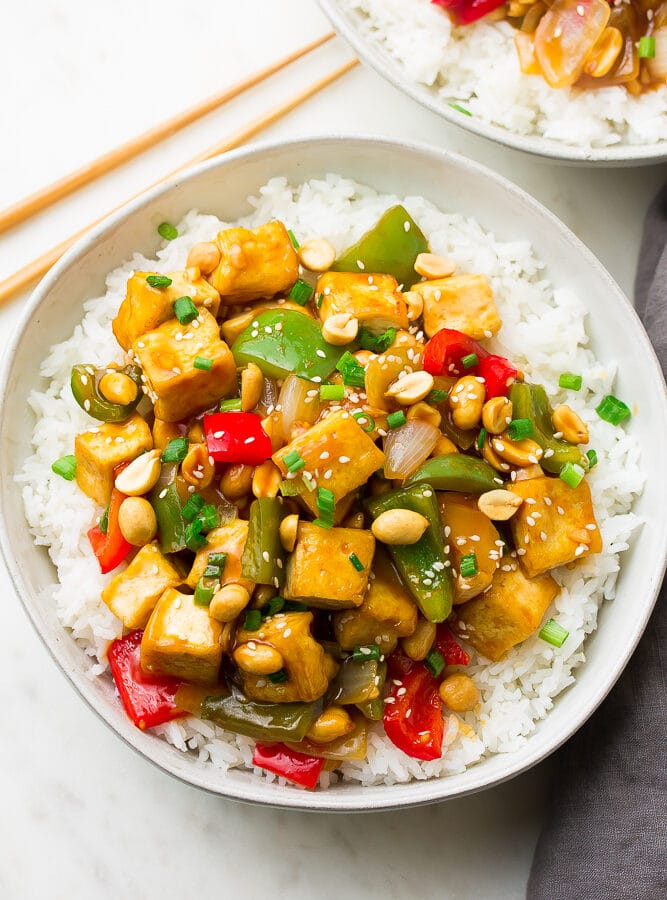 plate with white rice and kung pao tofu and peppers with peanuts on top