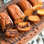 four pumpkin bread loaves on a cooling rack